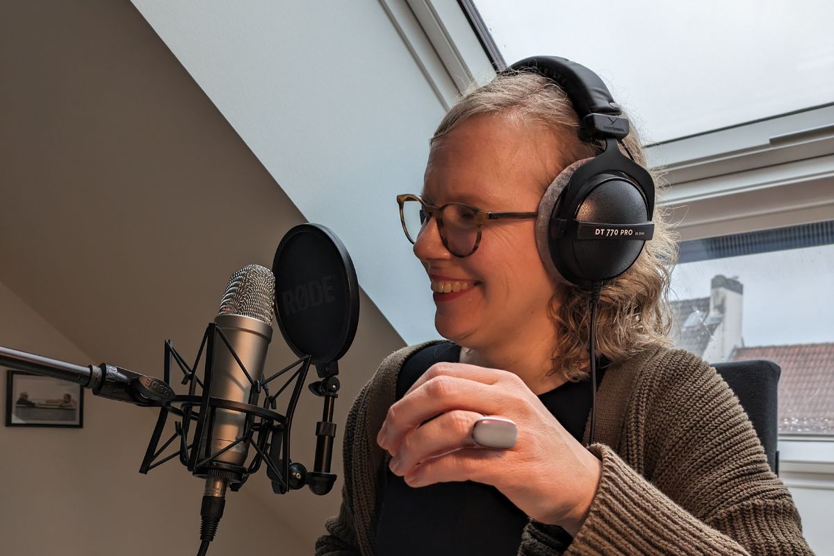 Mirjam Rosentreter moderiert mit Mikrofon, Kopfhörern und Popschutz